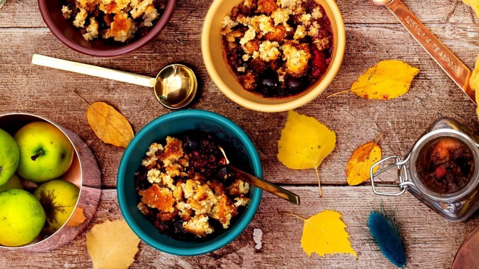 Bowls of berry walnut crumble with apples and autumn leaves