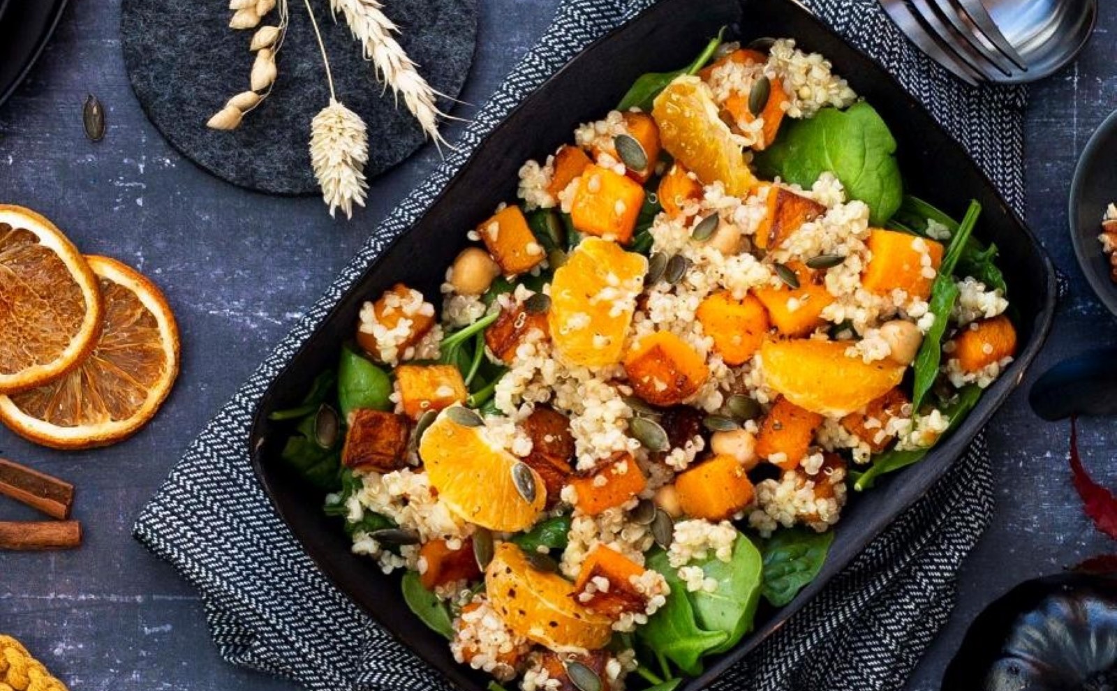 Pumpkin quinoa salad in black dish on a black and orange themed table