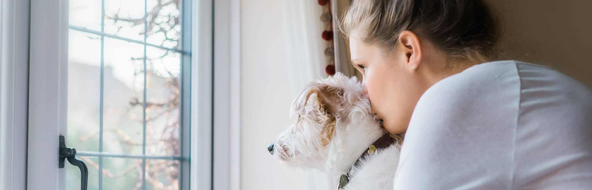 woman looking out window with dog